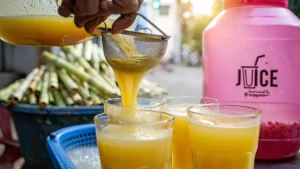 A refreshing glass of sugarcane juice is placed on a wooden table, highlighting its natural color and health benefits such as hydration, energy boost, improved digestion, and detoxification.